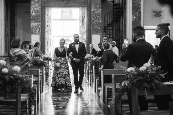 lo sposo in chiesa porge il braccio alla madre durante l'ingresso